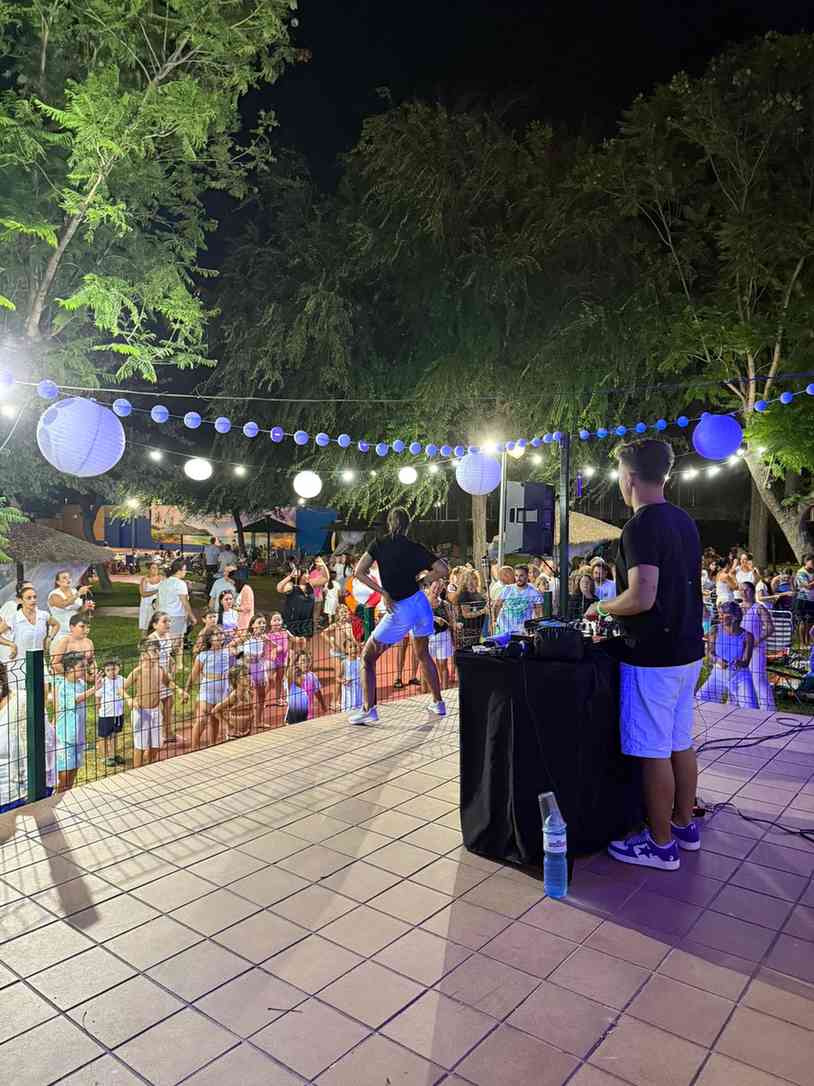 DJ y bailarín animando una fiesta nocturna al aire libre con luces de guirnalda