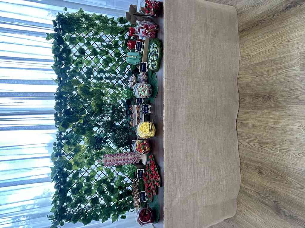 Mesa de candy bar decorada con hiedra artificial para una fiesta de adultos