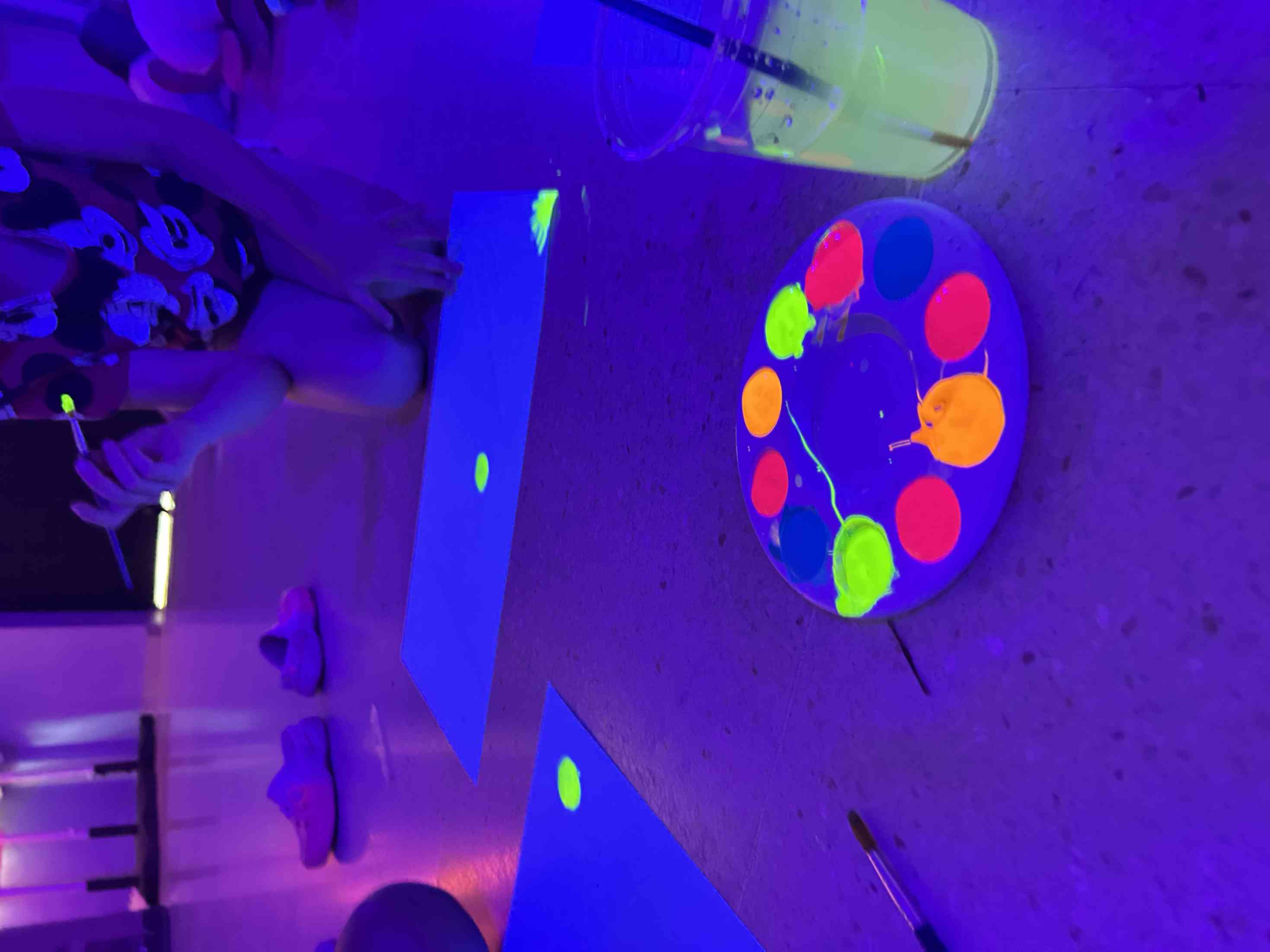 Actividad de pintura fluorescente bajo luz negra en un evento para adultos