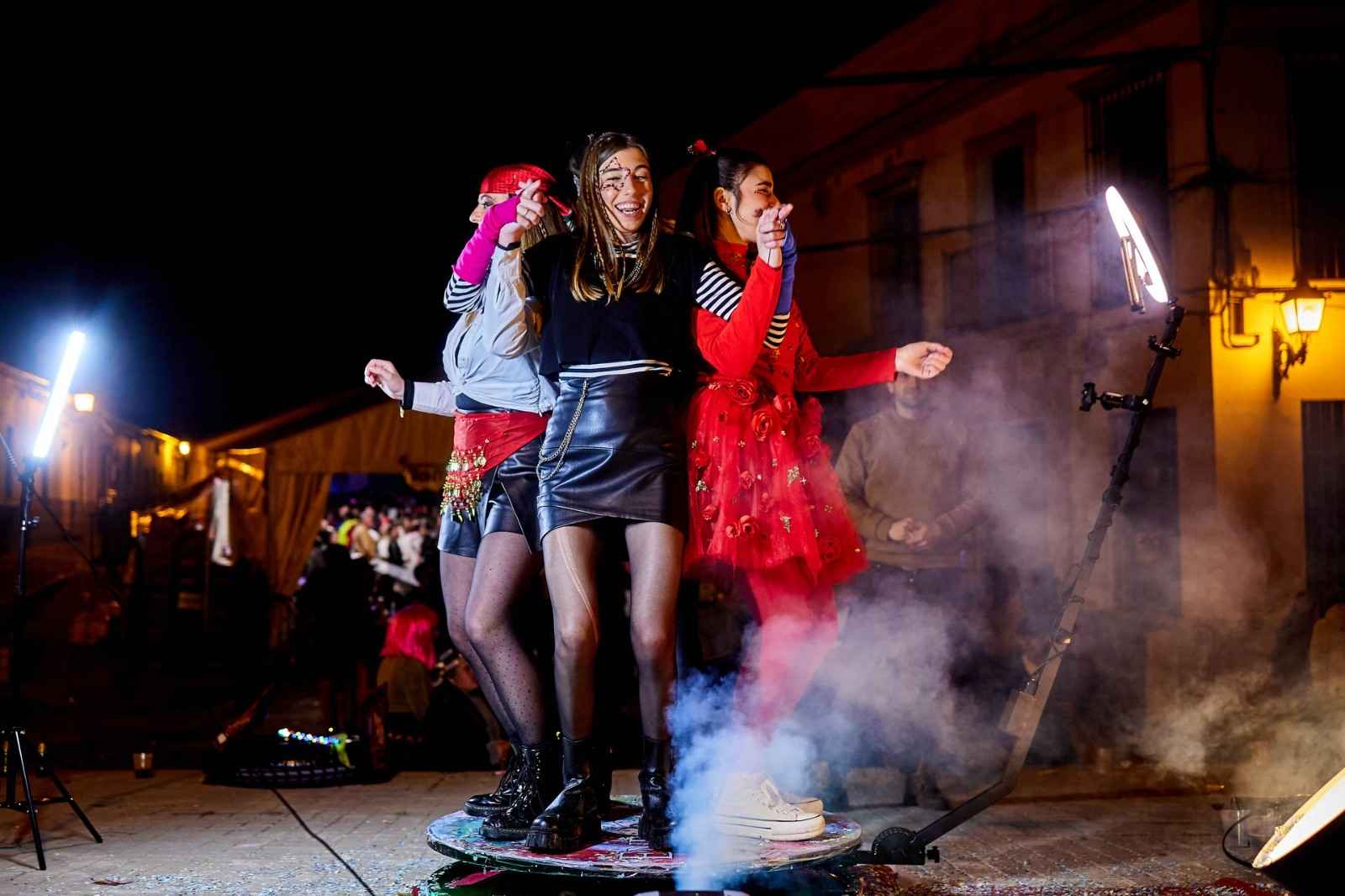 Grupo de amigas bailando y posando en un photocall nocturno con humo y luces