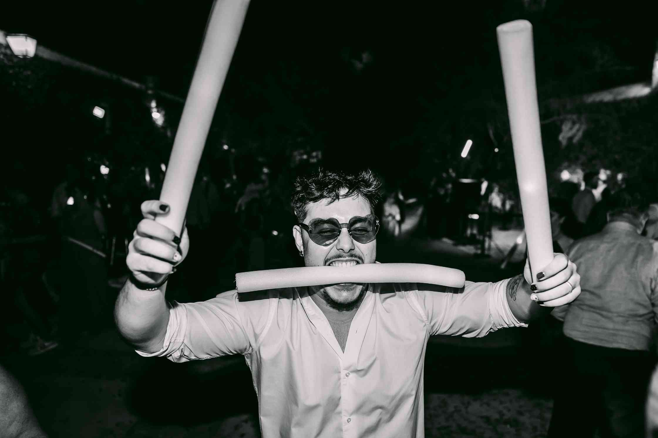 Invitado con gafas de corazón y tubos hinchables luminosos bailando en una fiesta Betta Party