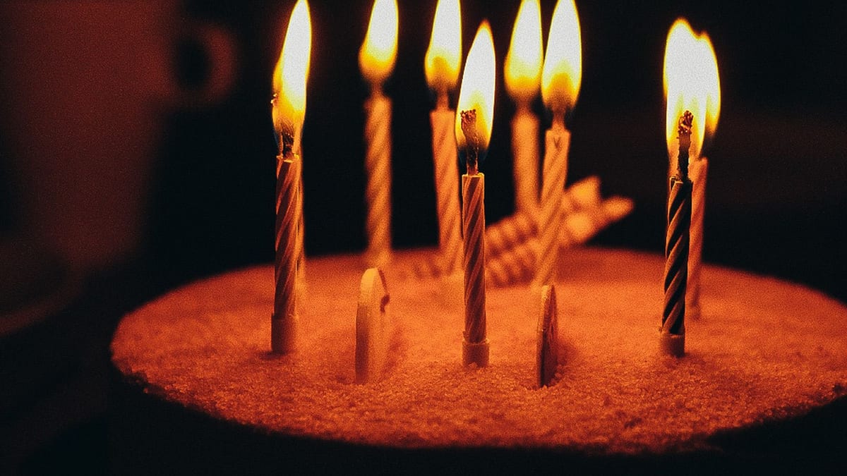 Tarta de cumpleaños con velas encendidas sobre fondo oscuro