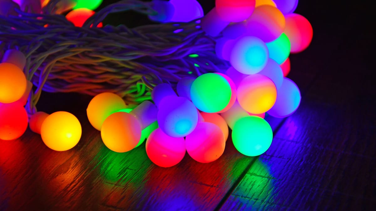 Guirnalda de bombillas de colores encendidas sobre una superficie de madera oscura