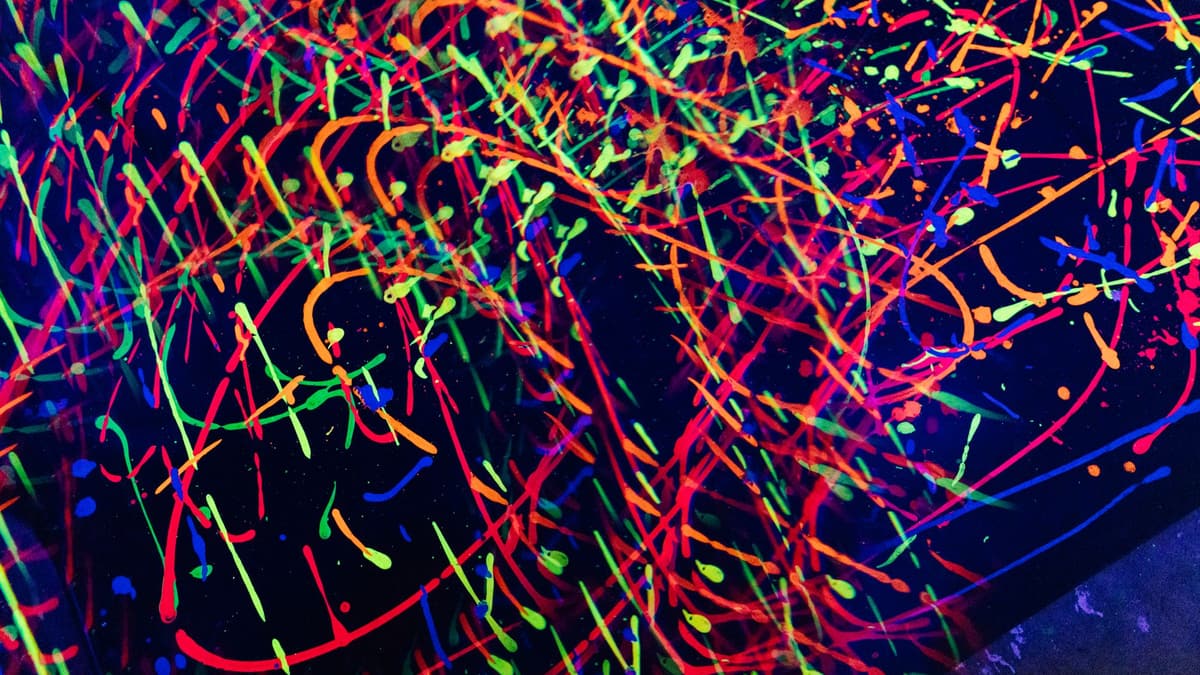 Salpicaduras de pintura fluorescente de varios colores sobre fondo negro bajo luz ultravioleta