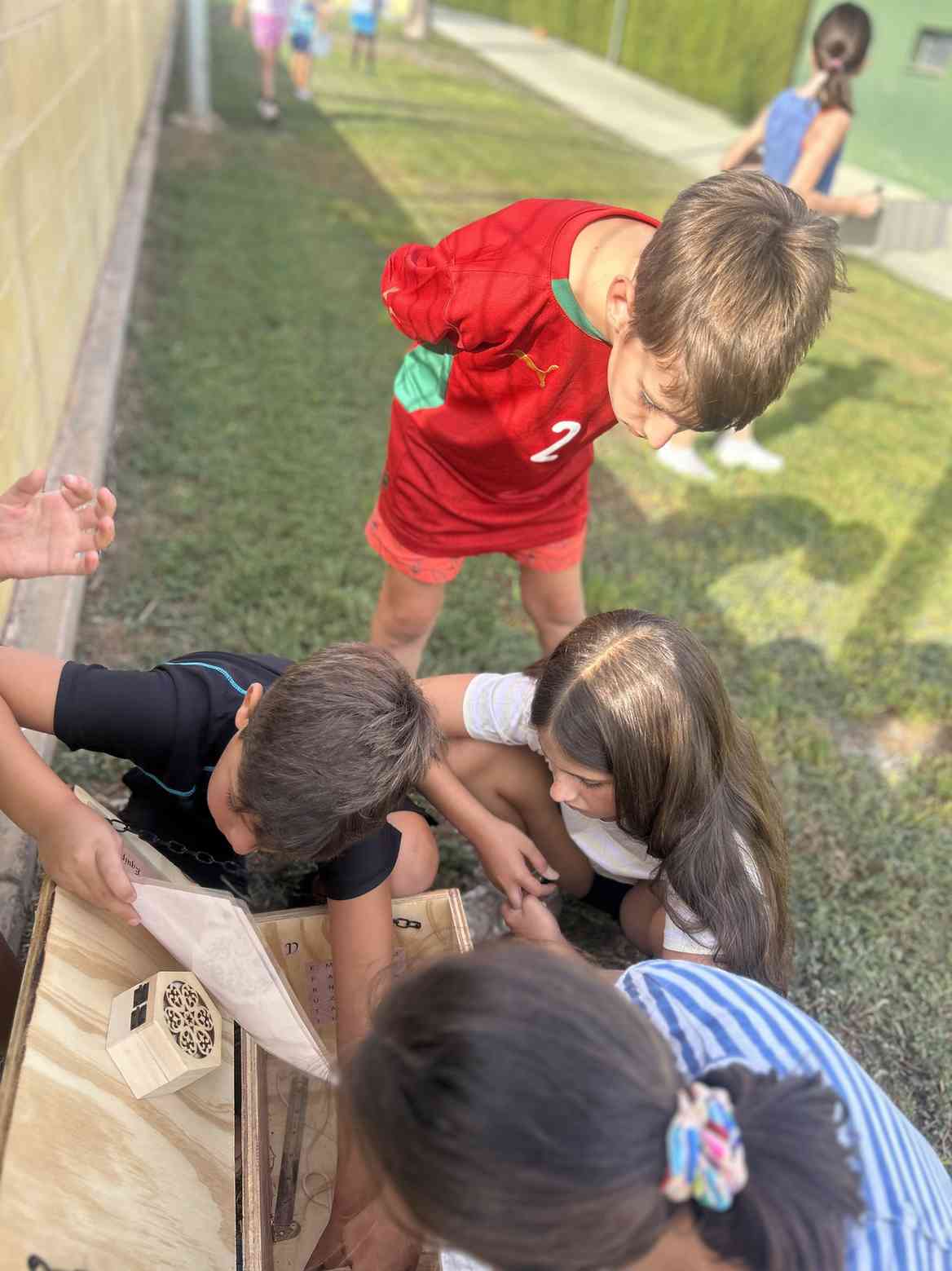 Grupo de niños agachados jugando a una gymkhana con un cofre de madera en el jardín
